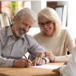 Brookwater Legal - Happy elderly couple joyfully signing property contract, symbolising a lifetime of shared memories and the excitement of a new chapter in their lives